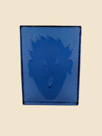 Rückseite der blauen Glasskulptur „Brick“ von Kiki Kogelnik mit reliefiertem Kopfmotiv